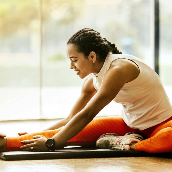 Person stretching on a yoga mat with vibrant energy lines around them.